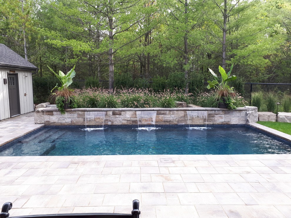 Example of a small transitional backyard concrete paver and rectangular pool fountain design