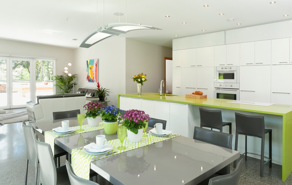 Design ideas for a large contemporary eat-in kitchen in Vancouver with concrete floors, an undermount sink, flat-panel cabinets, white cabinets, white appliances and with island.