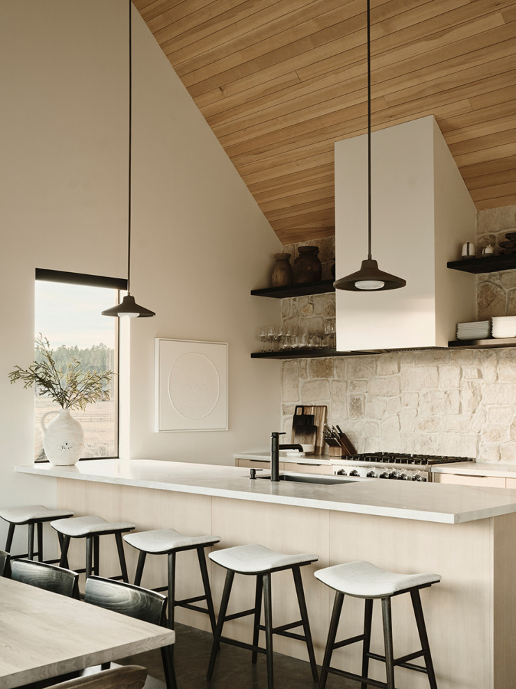 Design ideas for a country galley open plan kitchen in Phoenix with an undermount sink, flat-panel cabinets, light wood cabinets, quartz benchtops, white splashback, limestone splashback, panelled appliances, concrete floors, with island, grey floor, white benchtop and vaulted.