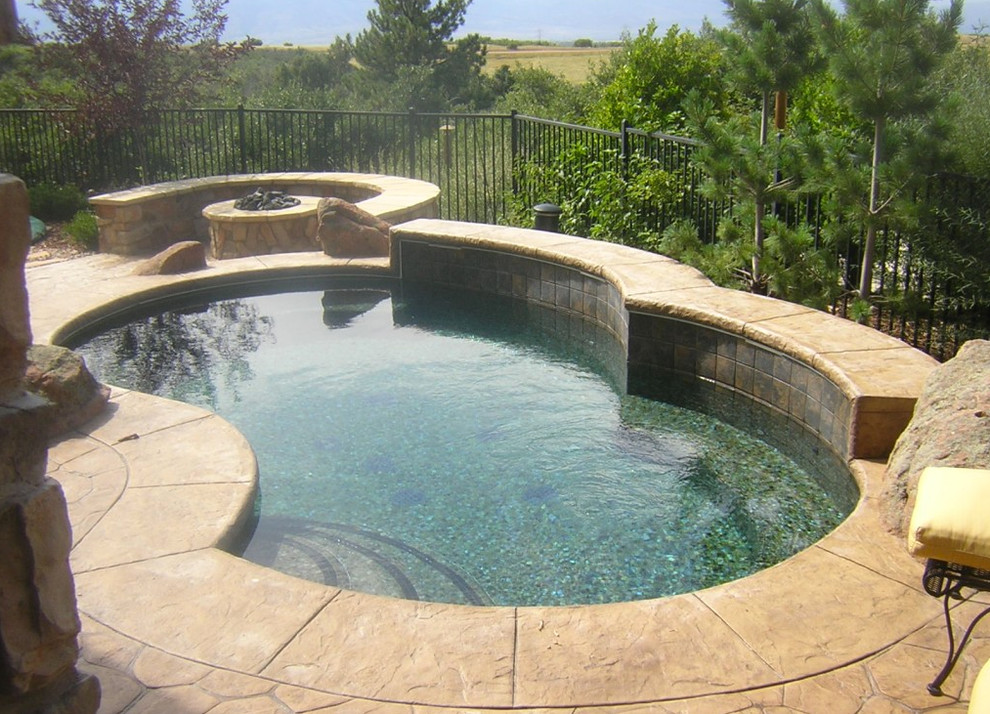 This is an example of a small backyard custom-shaped natural pool in Denver with a hot tub and natural stone pavers.