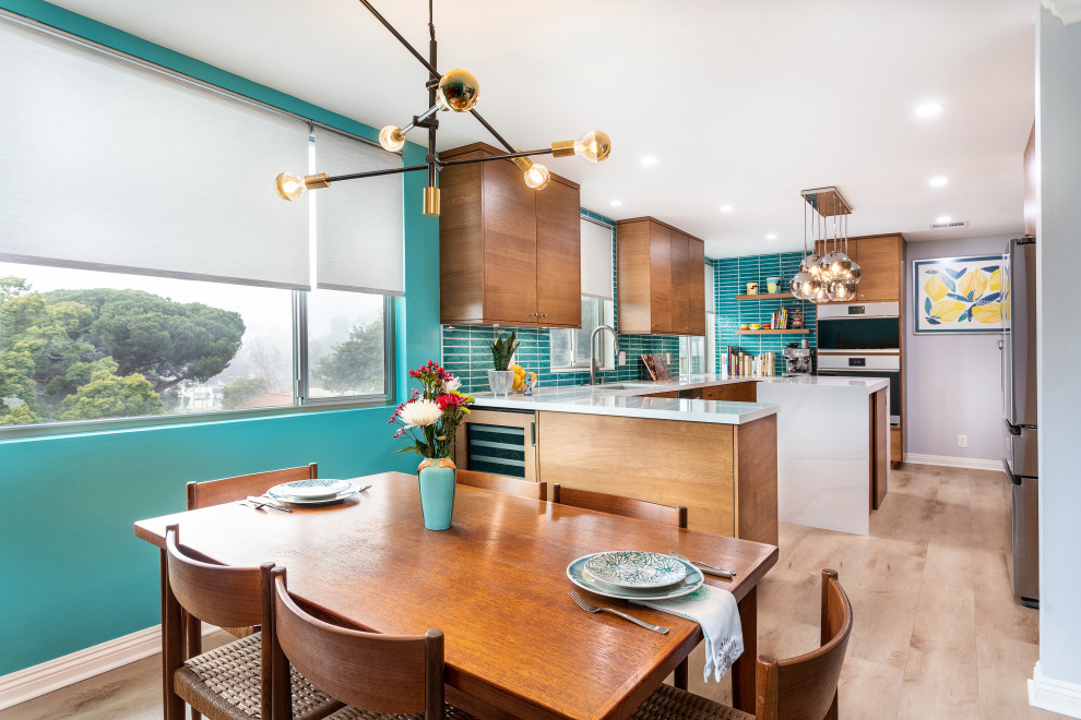 Photo of a small midcentury galley eat-in kitchen in Los Angeles with an undermount sink, flat-panel cabinets, medium wood cabinets, quartz benchtops, blue splashback, stainless steel appliances, laminate floors, with island and white benchtop.
