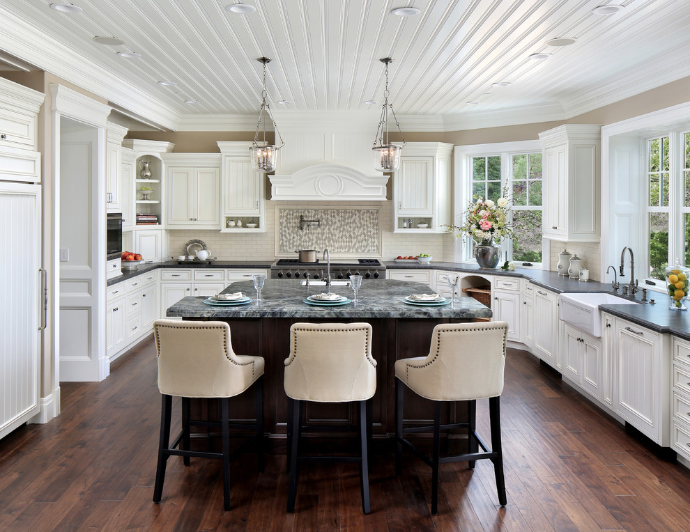 Design ideas for a traditional u-shaped kitchen in San Francisco with a farmhouse sink, recessed-panel cabinets, white cabinets, white splashback, stainless steel appliances, dark hardwood floors and with island.