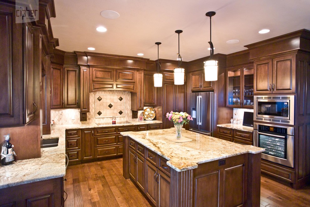 Mid-sized transitional u-shaped medium tone wood floor and brown floor enclosed kitchen photo with an undermount sink, raised-panel cabinets, medium tone wood cabinets, granite countertops, multicolored backsplash, porcelain backsplash, stainless steel appliances and an island