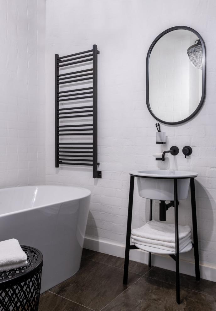 На фото: главная ванная комната среднего размера в стиле лофт с отдельно стоящей ванной, консольной раковиной и тумбой под одну раковину с