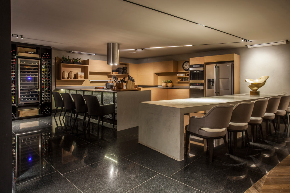 This is an example of a contemporary u-shaped kitchen in New York with flat-panel cabinets, light wood cabinets, beige splashback, timber splashback, stainless steel appliances, multiple islands, black floor and grey benchtop.
