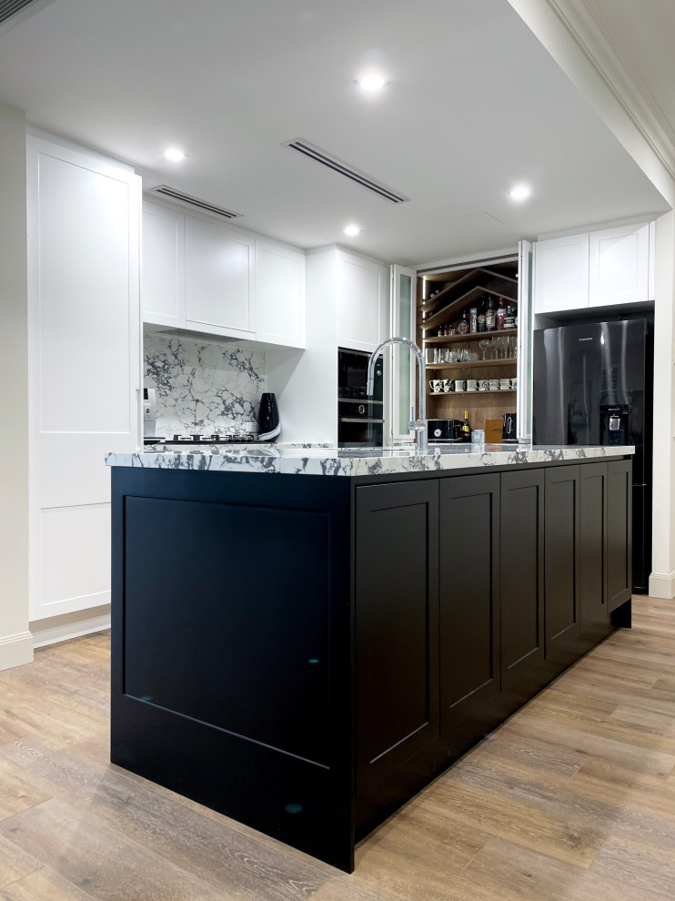 This is an example of a medium sized l-shaped kitchen/diner in Sydney with a submerged sink, shaker cabinets, black cabinets, engineered stone countertops, multi-coloured splashback, engineered quartz splashback, black appliances, light hardwood flooring, an island, brown floors and multicoloured worktops.