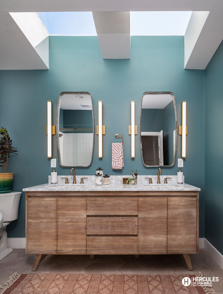 Inspiration for a mid-sized midcentury master bathroom in St Louis with flat-panel cabinets, medium wood cabinets, a two-piece toilet, blue walls, porcelain floors, an undermount sink, marble benchtops, grey floor, grey benchtops, a double vanity, a freestanding vanity and vaulted.