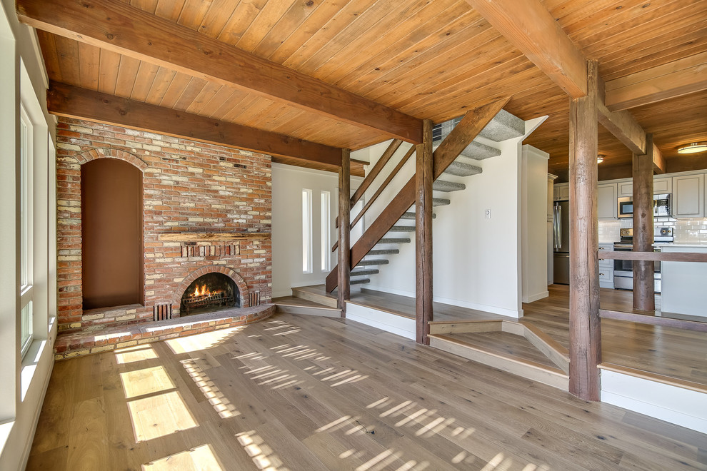 Photo of a mid-sized traditional open concept living room in Seattle with white walls, light hardwood floors, a standard fireplace, a brick fireplace surround, brown floor and no tv.