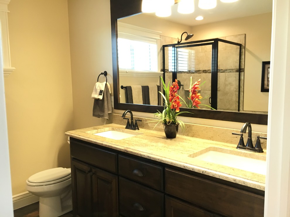 Mid-sized transitional master beige tile and porcelain tile porcelain tile drop-in bathtub photo with raised-panel cabinets, dark wood cabinets, a two-piece toilet, beige walls, an undermount sink and granite countertops