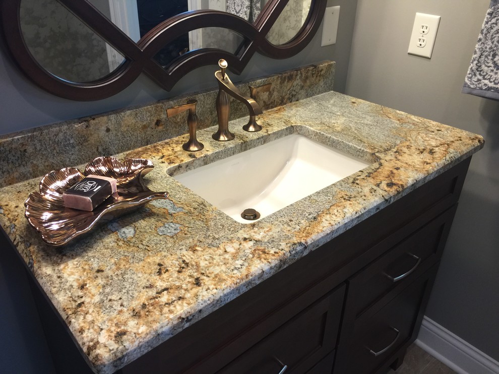 Photo of a large traditional master bathroom in Indianapolis with an undermount sink, granite benchtops, glass tile, grey walls, porcelain floors, recessed-panel cabinets and dark wood cabinets.