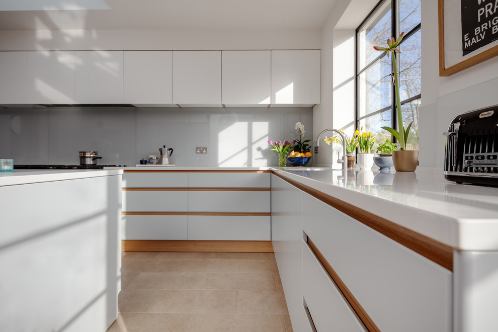 Design ideas for a large contemporary l-shaped separate kitchen in Cambridgeshire with a drop-in sink, flat-panel cabinets, grey cabinets, solid surface benchtops, grey splashback, glass sheet splashback, ceramic floors and with island.