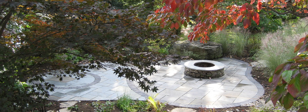 Design ideas for a mid-sized eclectic backyard garden in DC Metro with a fire feature and natural stone pavers.