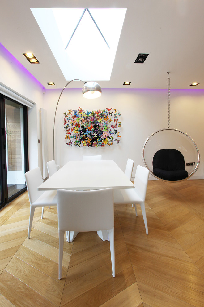 Photo of a mid-sized contemporary dining room in Manchester with white walls and light hardwood floors.
