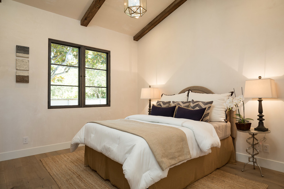 Inspiration for a mediterranean guest bedroom in San Luis Obispo with white walls, medium hardwood floors and brown floor.