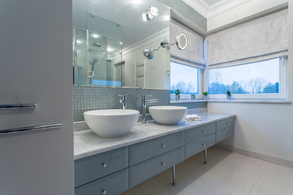 This is an example of a mid-sized traditional master bathroom in Los Angeles with raised-panel cabinets, blue cabinets, blue tile, mosaic tile, ceramic floors, a vessel sink and beige floor.