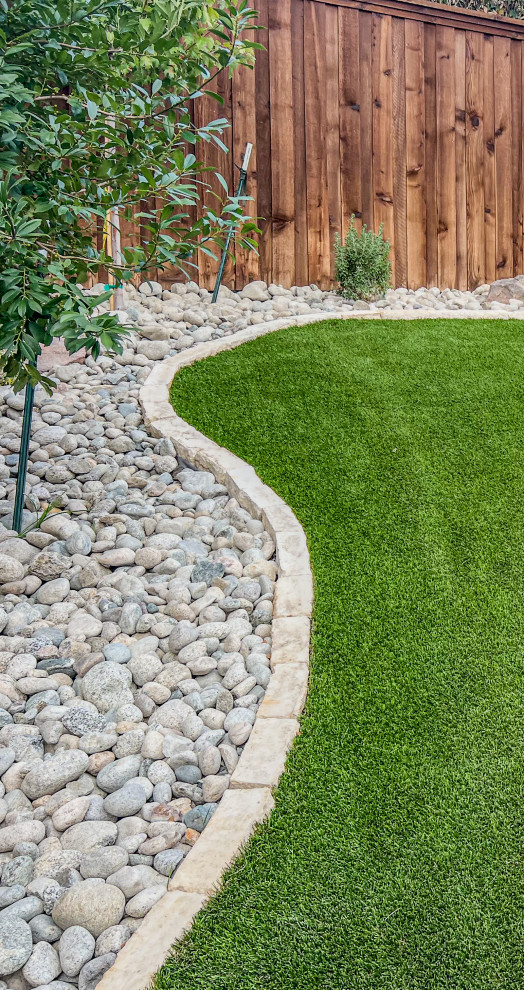 Photo of a mid-sized modern drought-tolerant and full sun backyard river rock and wood fence landscaping in Dallas with a pergola for summer.
