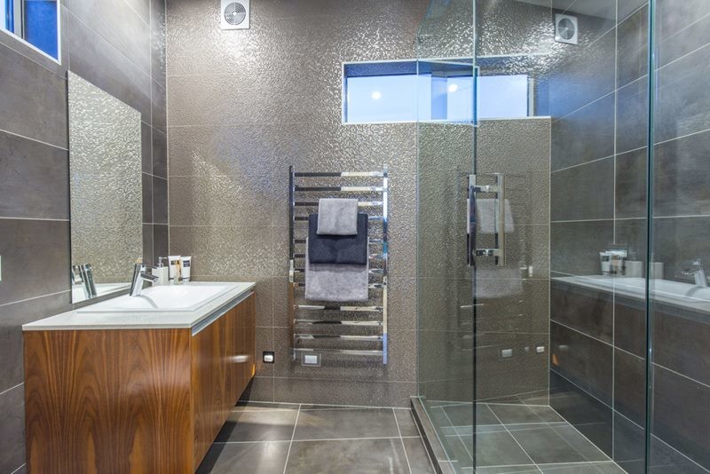Mid-sized contemporary master bathroom in Other with furniture-like cabinets, medium wood cabinets, a wall-mount toilet, brown tile, ceramic tile, ceramic floors, an integrated sink, brown floor and engineered quartz benchtops.
