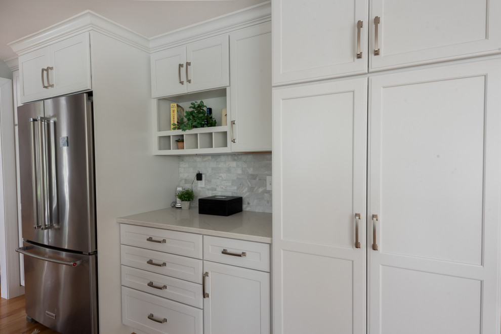 Example of a large transitional l-shaped medium tone wood floor, brown floor and coffered ceiling eat-in kitchen design in Boston with an undermount sink, shaker cabinets, white cabinets, quartz countertops, gray backsplash, subway tile backsplash, stainless steel appliances, an island and white countertops
