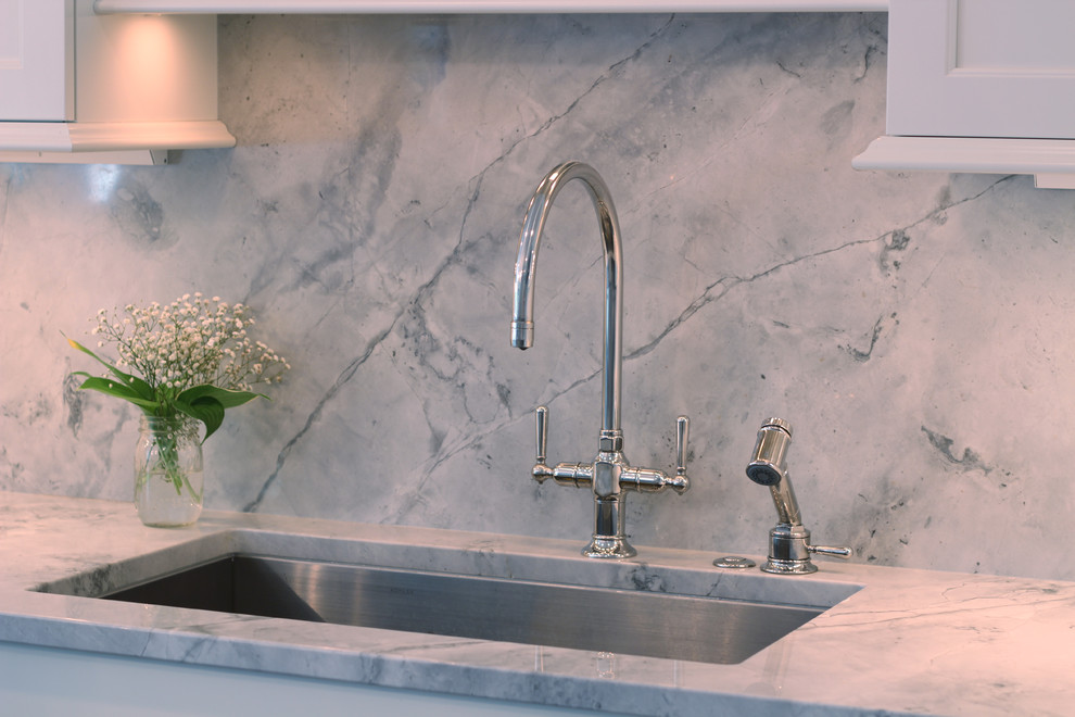 Example of a mid-sized transitional l-shaped dark wood floor eat-in kitchen design with a double-bowl sink, recessed-panel cabinets, white cabinets, stone slab backsplash, stainless steel appliances, an island, quartzite countertops and white backsplash