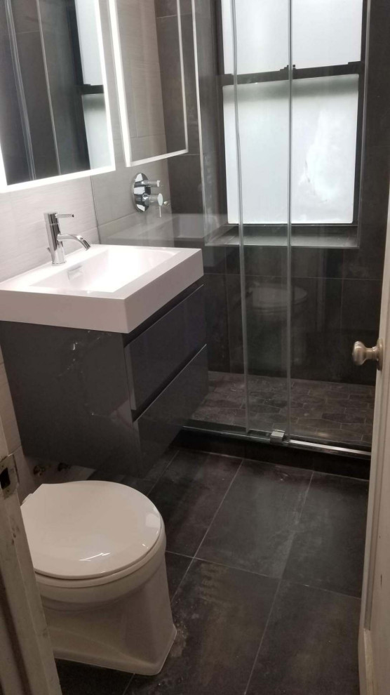 Photo of a small modern master bathroom in New York with flat-panel cabinets, grey cabinets, a double shower, a one-piece toilet, white tile, porcelain tile, white walls, porcelain floors, a console sink, glass benchtops, grey floor, a sliding shower screen, white benchtops, a single vanity and a floating vanity.