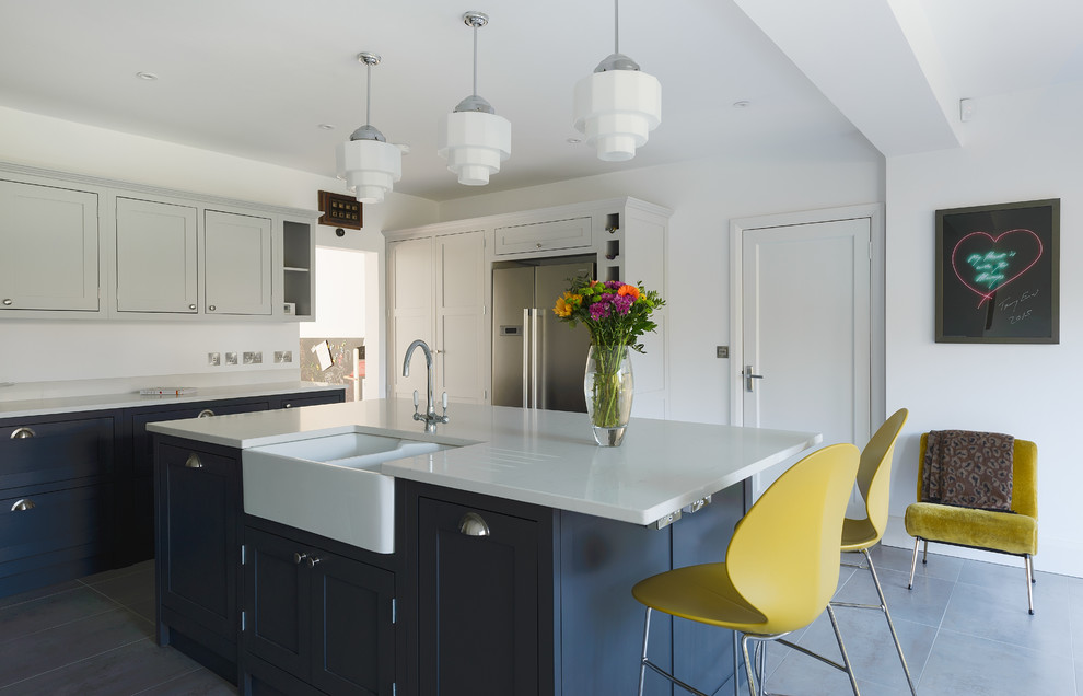 Inspiration for a mid-sized transitional u-shaped eat-in kitchen in Gloucestershire with shaker cabinets, ceramic floors, with island, blue cabinets, white splashback, stainless steel appliances, a farmhouse sink and blue floor.