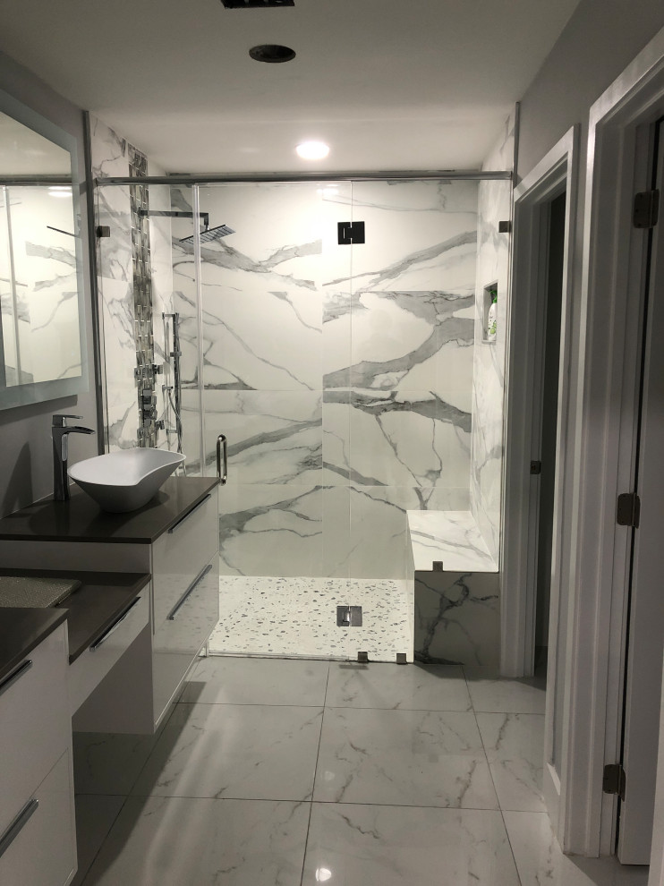 Inredning av ett modernt mellanstort grå grått en-suite badrum, med vita skåp, en toalettstol med hel cisternkåpa, svart och vit kakel, porslinskakel, vita väggar, klinkergolv i porslin, ett väggmonterat handfat, bänkskiva i kvartsit och flerfärgat golv