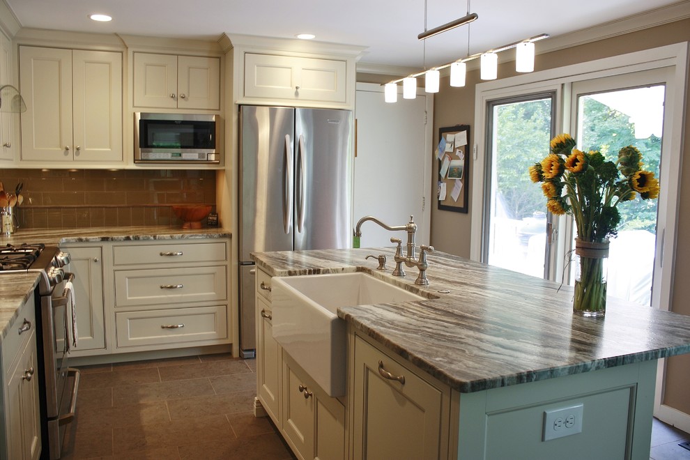 This is an example of a mid-sized transitional l-shaped eat-in kitchen in Philadelphia with a farmhouse sink, recessed-panel cabinets, white cabinets, quartzite benchtops, brown splashback, glass tile splashback, stainless steel appliances, porcelain floors and with island.