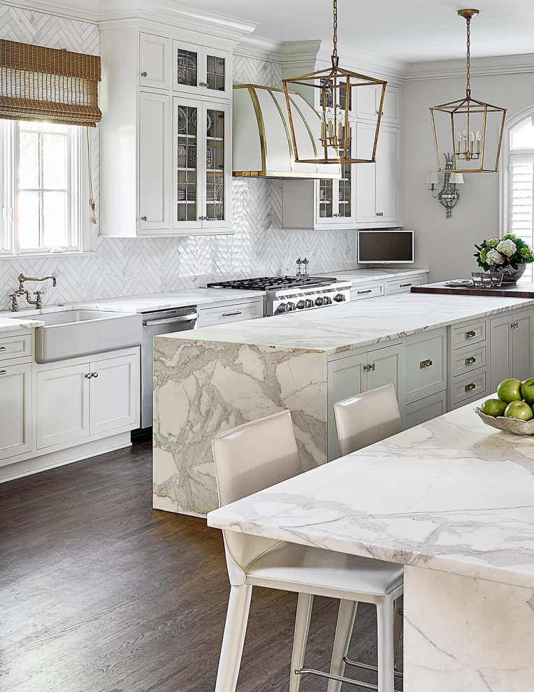 Example of a large transitional galley medium tone wood floor and brown floor eat-in kitchen design in Charlotte with a farmhouse sink, shaker cabinets, white cabinets, gray backsplash, glass tile backsplash, stainless steel appliances, an island and white countertops