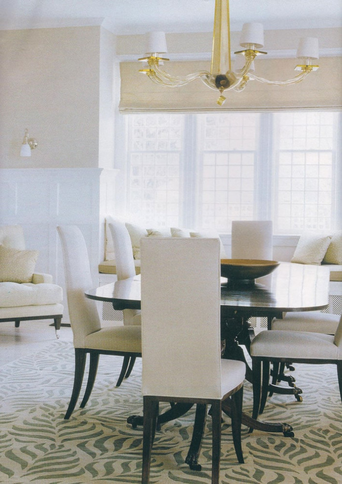 Immagine di una sala da pranzo aperta verso il soggiorno contemporanea di medie dimensioni con pareti beige, parquet chiaro, camino classico e cornice del camino in cemento