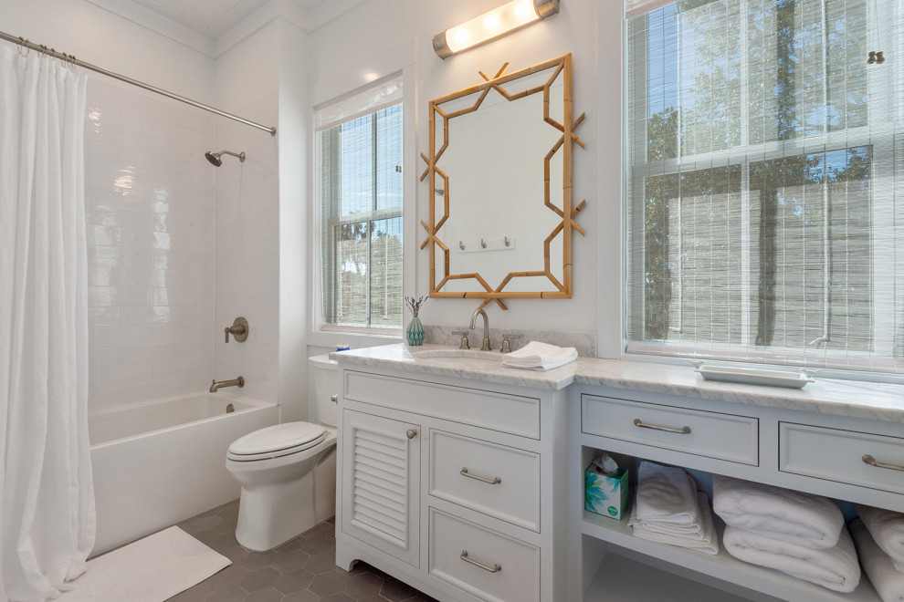 Design ideas for a mid-sized traditional master bathroom in New Orleans with flat-panel cabinets, white cabinets, an alcove tub, an alcove shower, a two-piece toilet, white tile, ceramic tile, white walls, ceramic floors, an undermount sink, marble benchtops, grey floor, a shower curtain, white benchtops, a single vanity and a built-in vanity.