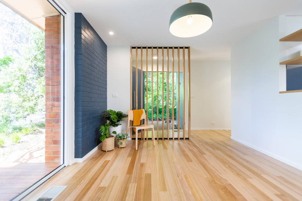 Design ideas for a modern entryway in Canberra - Queanbeyan with medium hardwood floors and brick walls.