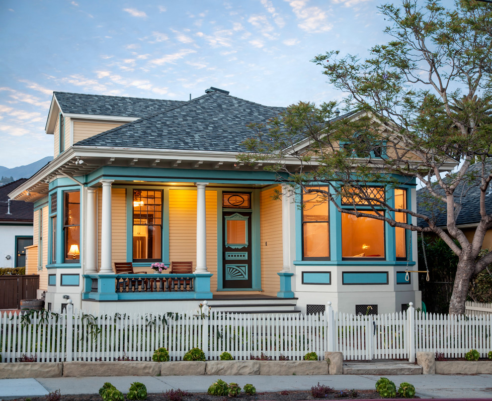 Design ideas for a mid-sized traditional two-storey yellow exterior in Santa Barbara with wood siding and a hip roof.