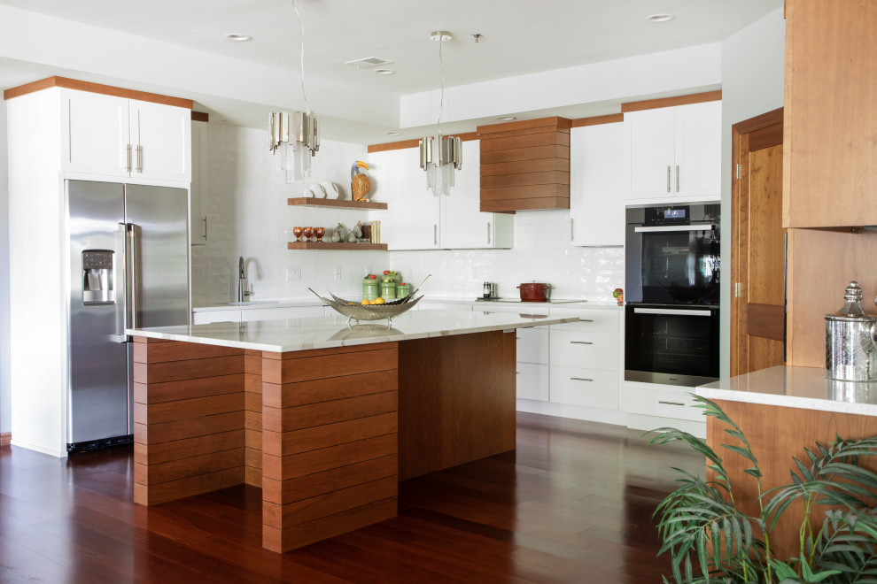 This is an example of a large contemporary l-shaped eat-in kitchen in Other with an undermount sink, shaker cabinets, quartz benchtops, white splashback, porcelain splashback, stainless steel appliances, with island, brown floor, white benchtop, white cabinets and dark hardwood floors.