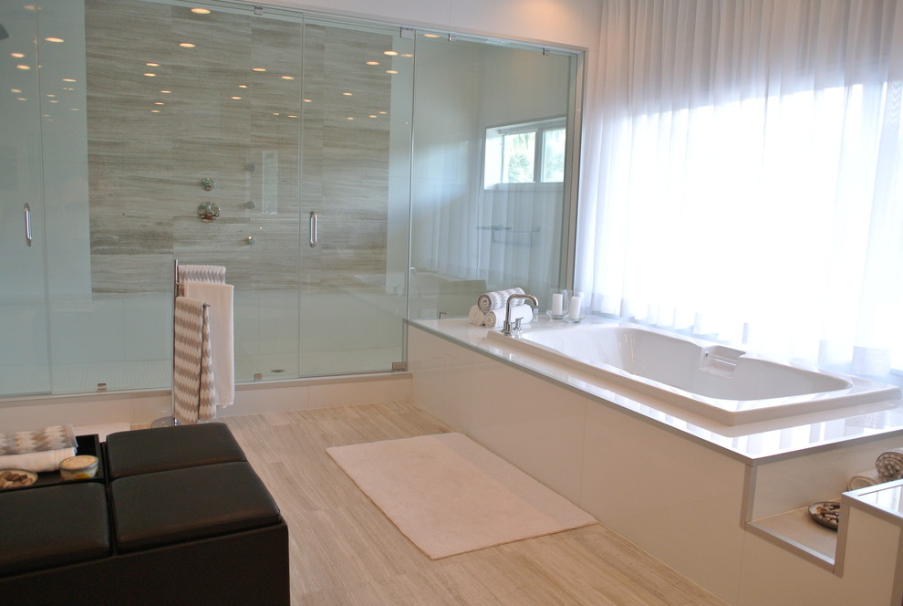 Design ideas for a large contemporary master bathroom in Miami with furniture-like cabinets, medium wood cabinets, a drop-in tub, a double shower, a one-piece toilet, white tile, stone slab, white walls, ceramic floors, a drop-in sink and glass benchtops.