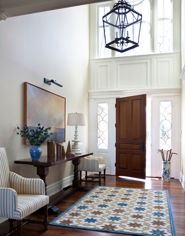 Photo of a mid-sized traditional foyer in New York with white walls, dark hardwood floors, a single front door and a dark wood front door.