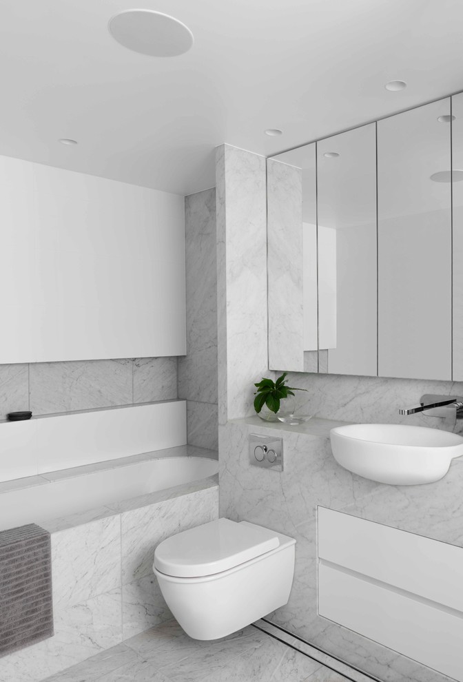 Photo of a mid-sized contemporary 3/4 bathroom in Sydney with flat-panel cabinets, grey cabinets, an undermount tub, a wall-mount toilet, gray tile, marble, white walls, marble floors, a wall-mount sink, marble benchtops, grey floor and grey benchtops.