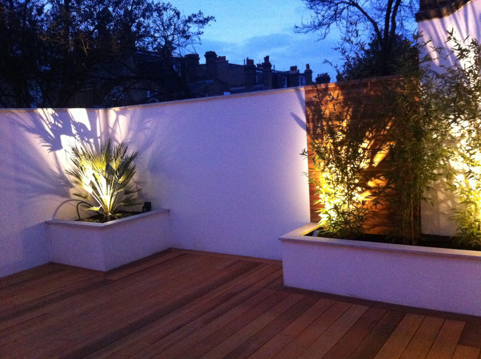 Small contemporary backyard partial sun xeriscape in London with a retaining wall and decking.