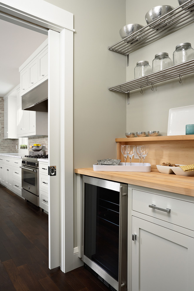 Large transitional dark wood floor open concept kitchen photo in Minneapolis with a farmhouse sink, recessed-panel cabinets, white cabinets, gray backsplash, ceramic backsplash, stainless steel appliances, an island and wood countertops