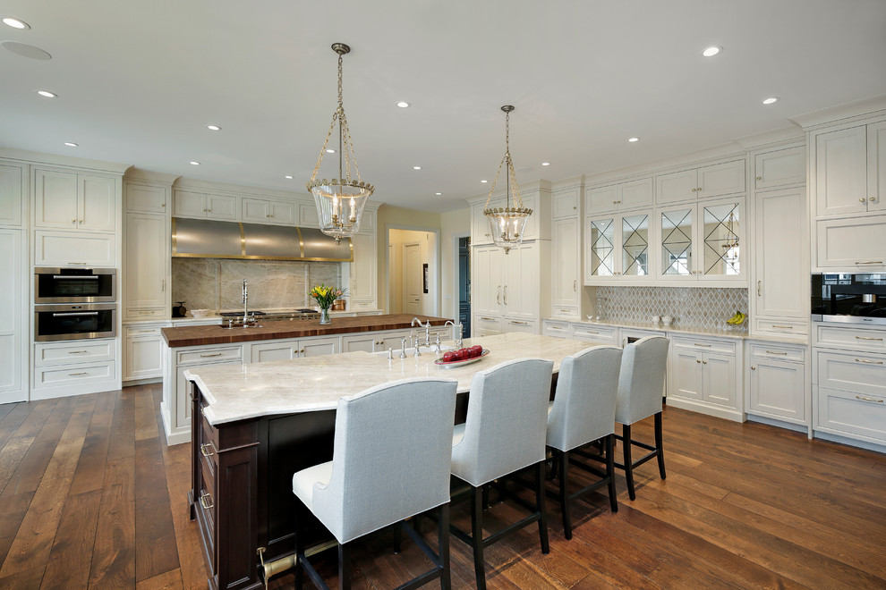 Large traditional open plan kitchen in Chicago with recessed-panel cabinets, medium hardwood floors and multiple islands.