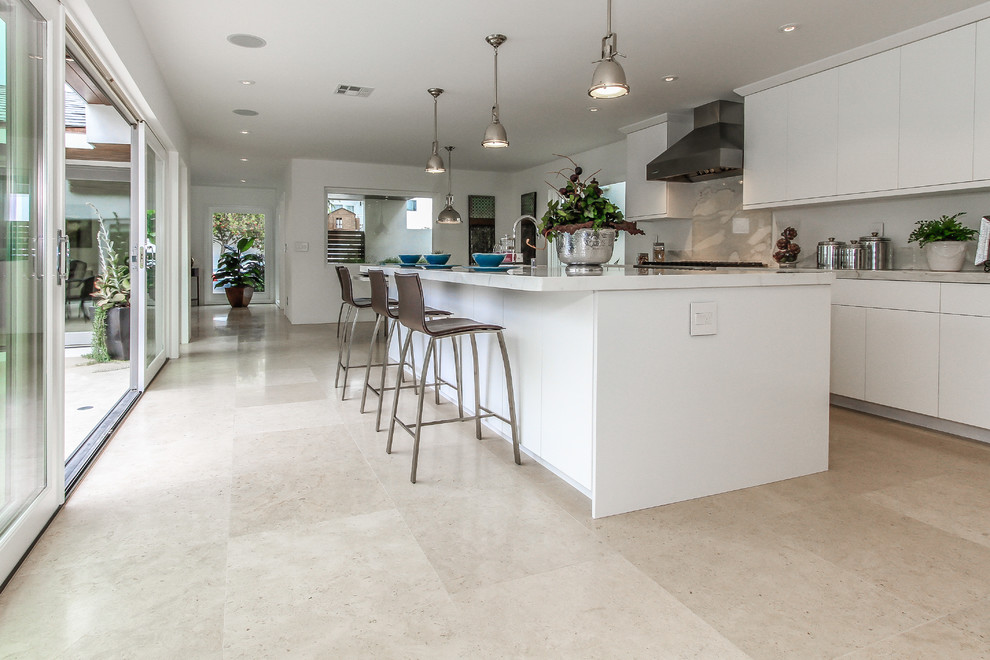 Tropical u-shaped eat-in kitchen in Orange County with a single-bowl sink, flat-panel cabinets, white cabinets, marble benchtops, white splashback and stainless steel appliances.