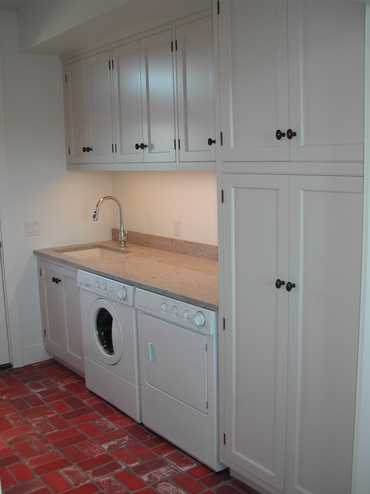Mid-sized traditional single-wall dedicated laundry room in New York with an undermount sink, beaded inset cabinets, white cabinets, quartz benchtops, white walls, brick floors, a side-by-side washer and dryer, red floor and beige benchtop.