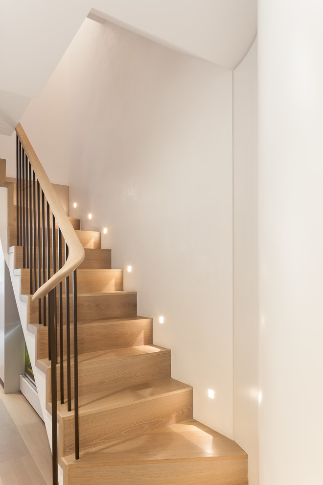 Mid-sized contemporary wood curved staircase in London with wood risers and wood railing.