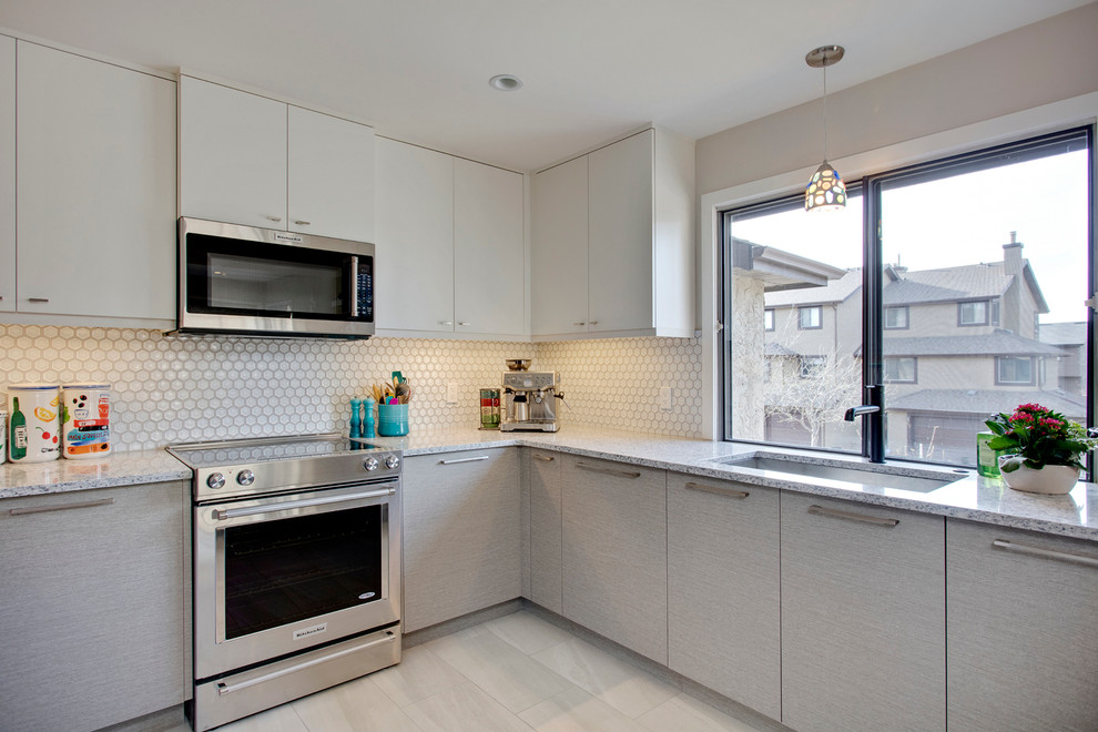 Enclosed kitchen - mid-sized modern u-shaped porcelain tile and gray floor enclosed kitchen idea in Calgary with an undermount sink, flat-panel cabinets, white cabinets, quartz countertops, white backsplash, ceramic backsplash, stainless steel appliances and a peninsula
