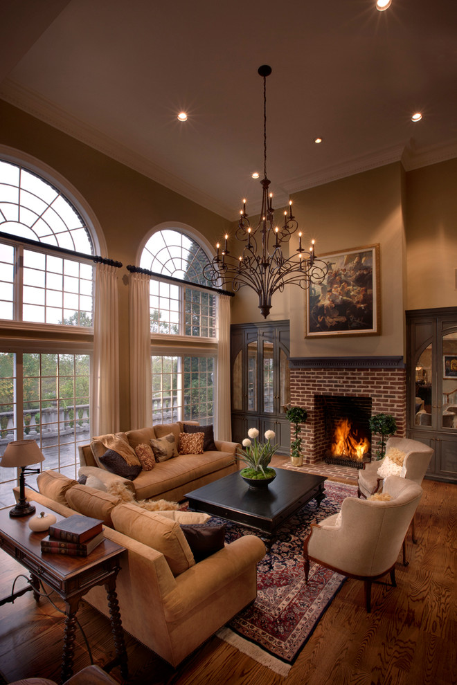 Design ideas for a large traditional open concept living room in Other with beige walls, a standard fireplace, a brick fireplace surround, a concealed tv, medium hardwood floors and brown floor.