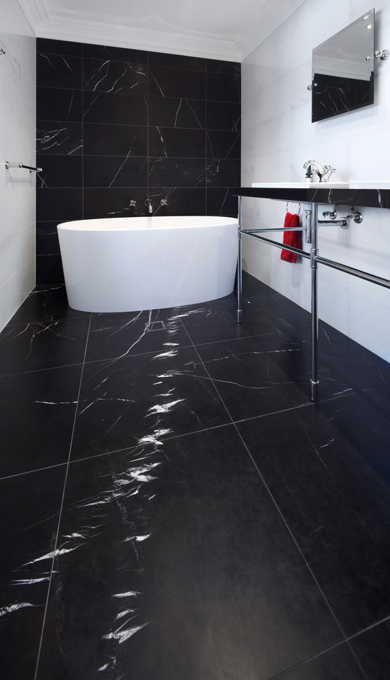 This is an example of a large contemporary master wet room bathroom in Sydney with a freestanding tub, black tile, black and white tile, white tile, marble floors, a console sink, black floor and a hinged shower door.