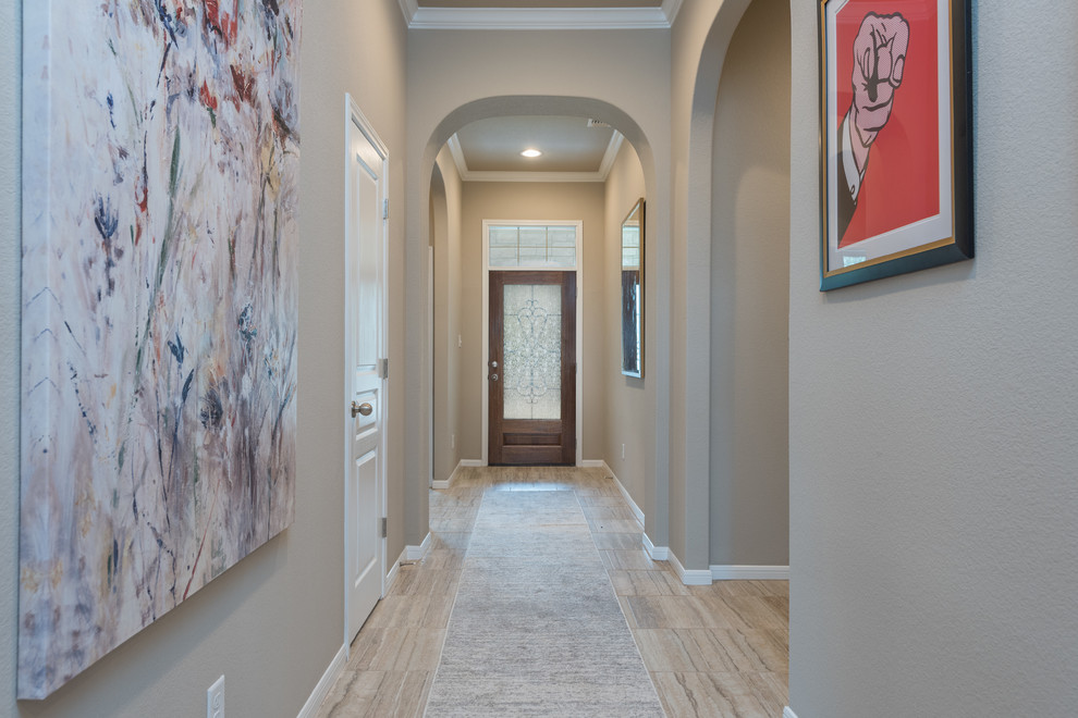 This is an example of a mid-sized transitional foyer in Austin with beige walls, ceramic floors, a pivot front door, a dark wood front door and beige floor.