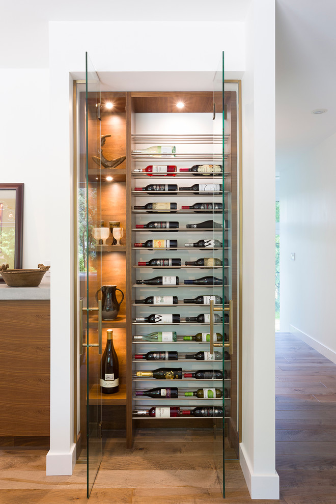 Inspiration for a small midcentury wine cellar in Other with light hardwood floors and storage racks.
