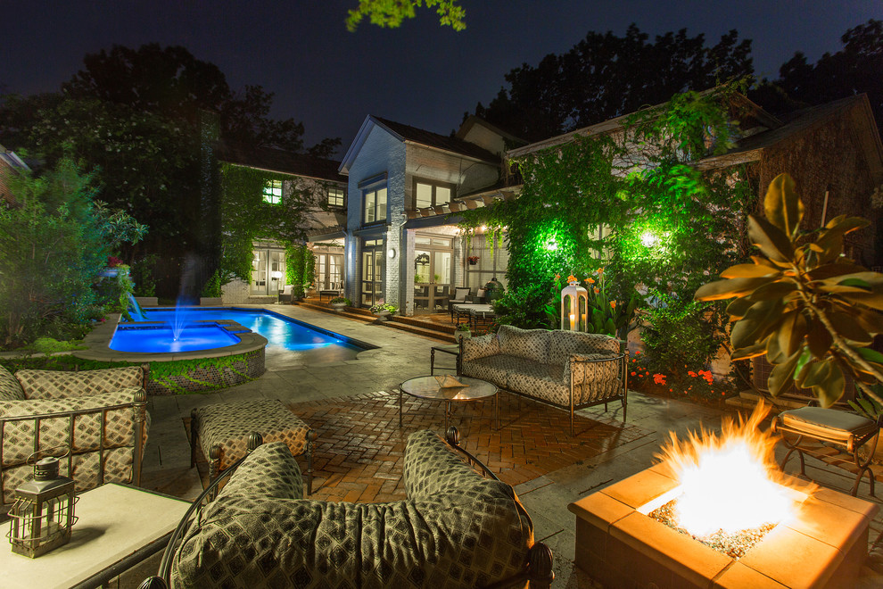 Photo of a mid-sized traditional backyard rectangular lap pool in Dallas with a water feature and natural stone pavers.