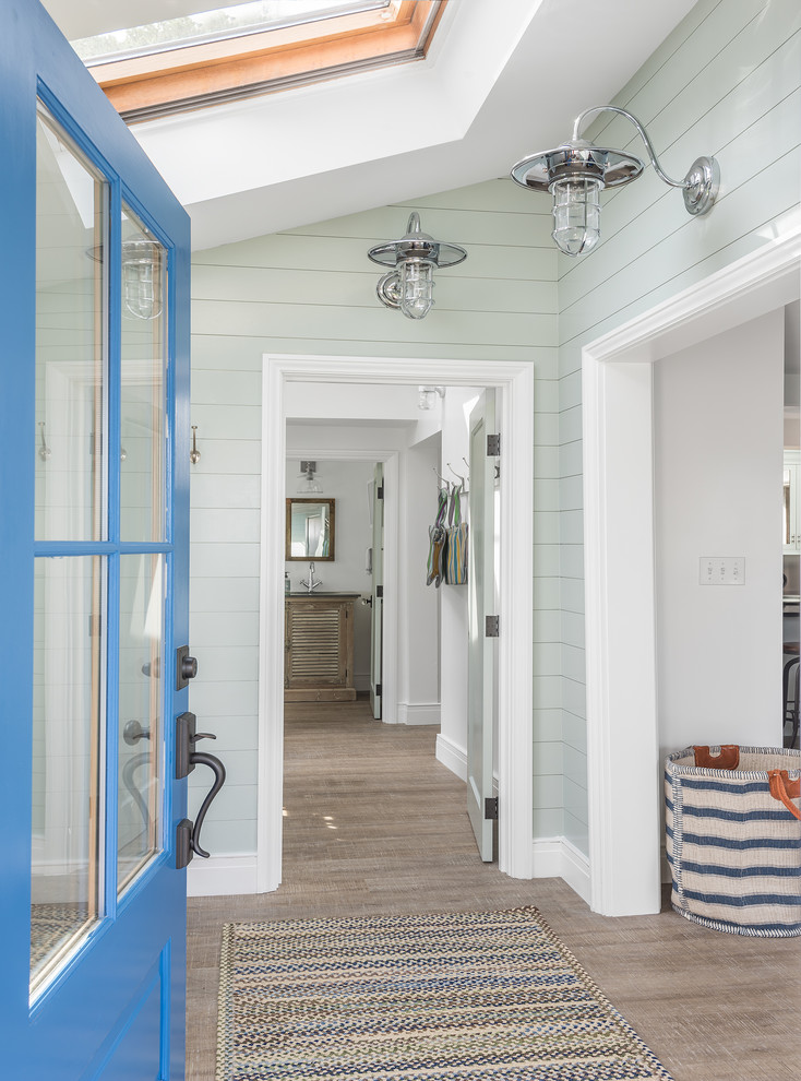 This is an example of a beach style front door in Portland Maine with blue walls, light hardwood floors, a single front door and a blue front door.