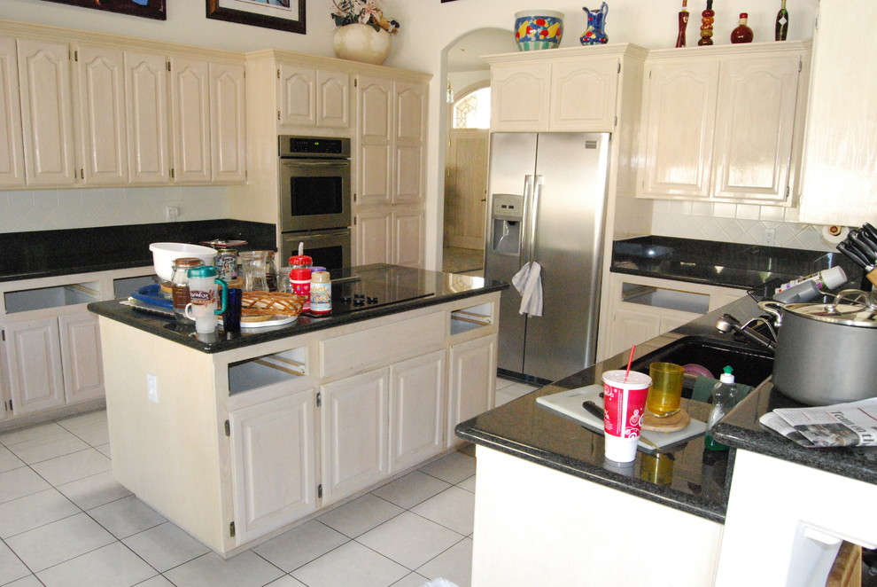 Example of a mid-sized transitional u-shaped ceramic tile and white floor eat-in kitchen design in Orange County with an undermount sink, raised-panel cabinets, light wood cabinets, granite countertops, white backsplash, ceramic backsplash, stainless steel appliances and an island